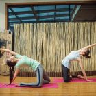 woman in white tank top and blue leggings doing yoga on purple yoga mat