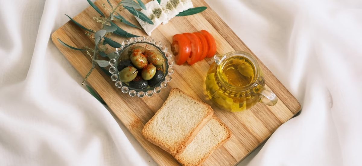 A delicious assortment of olives, cheese, tomatoes, and bread arranged on a wooden board.