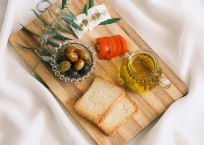 A delicious assortment of olives, cheese, tomatoes, and bread arranged on a wooden board.
