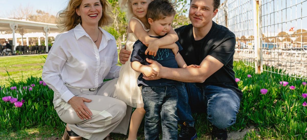 Family of four enjoying a sunny day outdoors in Kemer, smiling and spending quality time together.