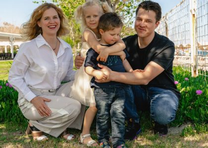 Family of four enjoying a sunny day outdoors in Kemer, smiling and spending quality time together.